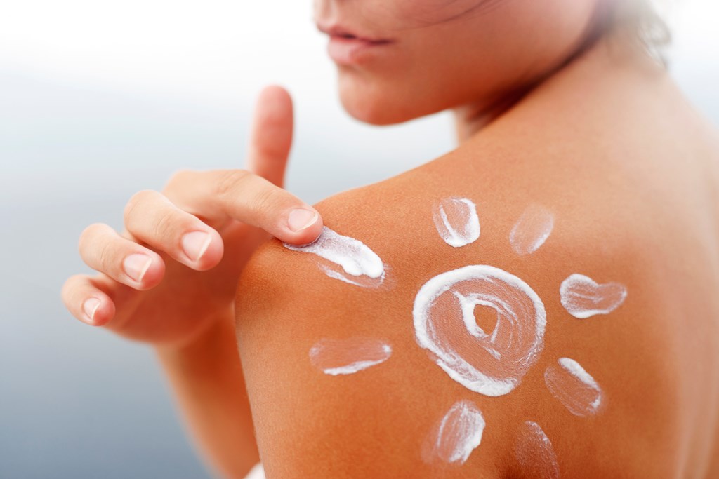 Woman's shoulder with sunscreen lotion in shape of sun.